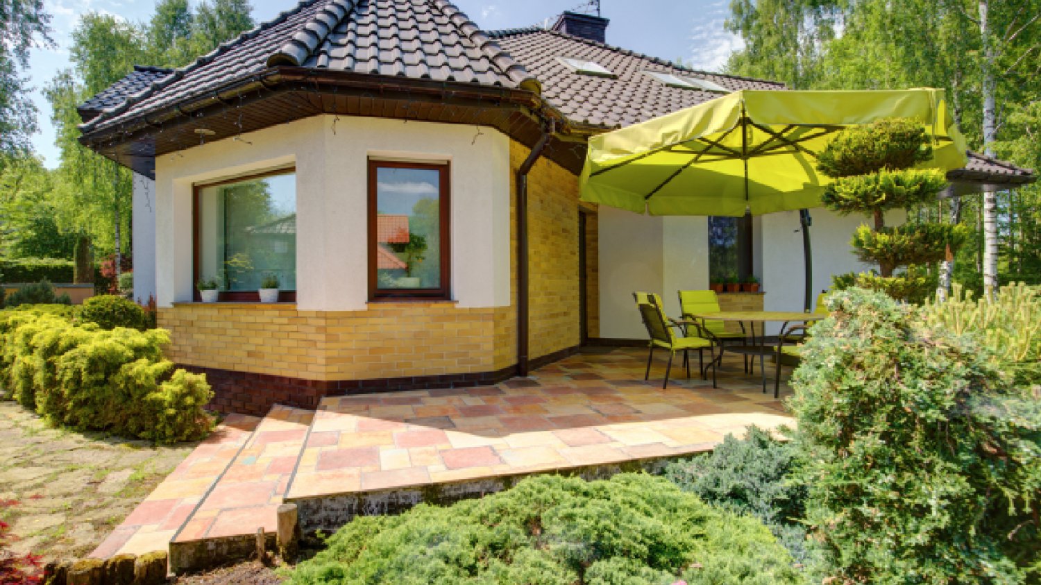 biały ekskluzywny dom z przestrzenią tarasową, ogrodem i parasolem
