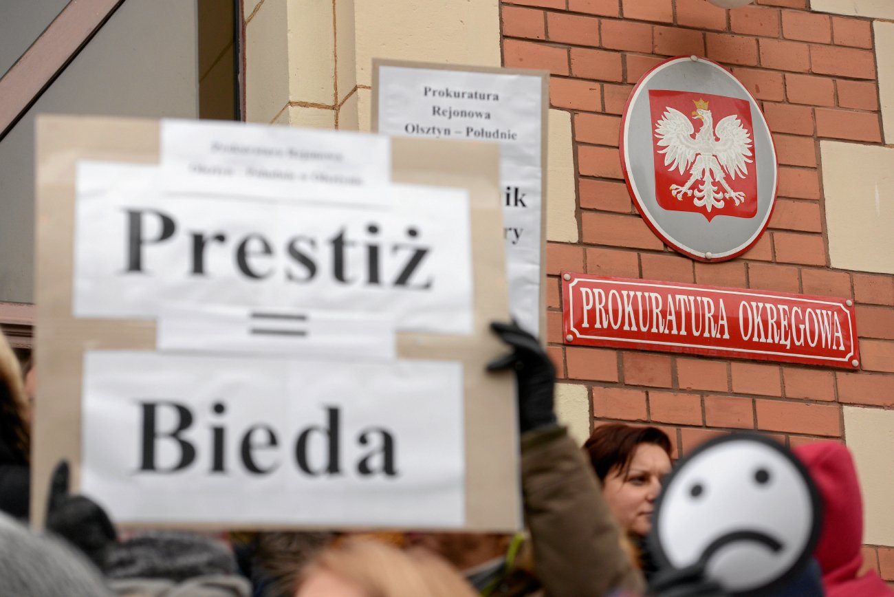 Protest pracowników prokuratury, na pierwszym planie baner z napisem "prestiż = bieda"