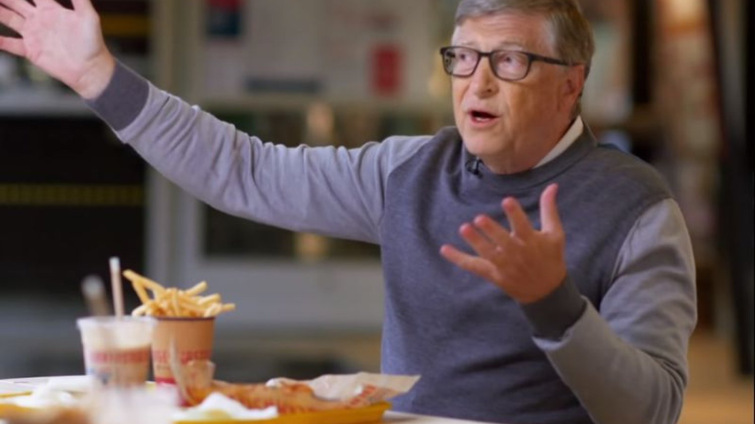 Bill Gates je frytki i rozkłada ręce.