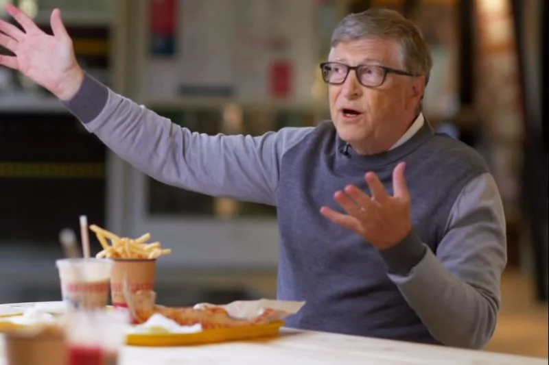 Bill Gates je frytki i rozkłada ręce.