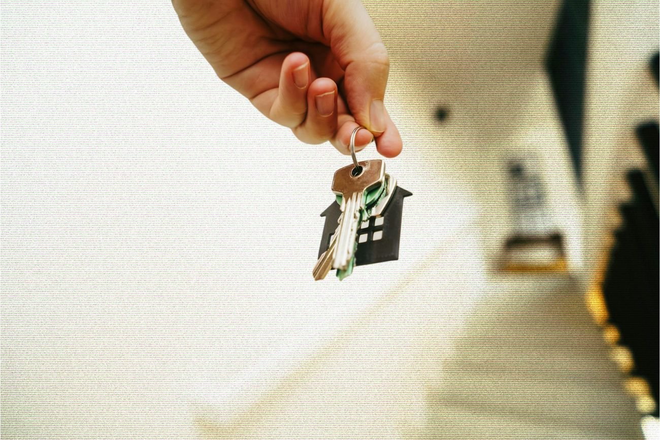 Dłoń trzymająca klucze z breloczkiem w kształcie domu.