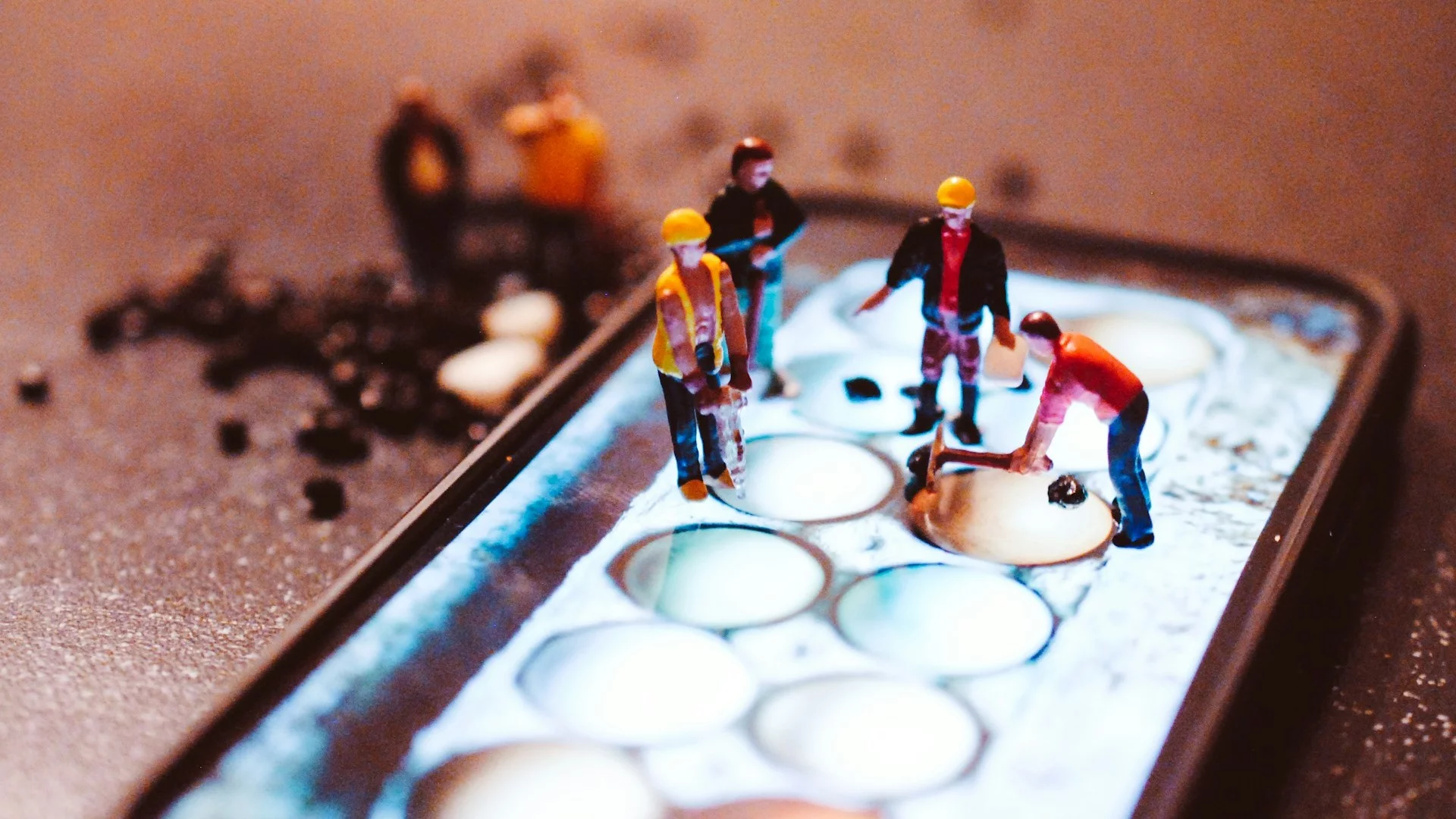 Grafika przedstawiająca pracowników w kaskach stojących na ogromnym smartfonie. Zawody, w których dużo się zarabia, to często te, gdzie brakuje pracowników.