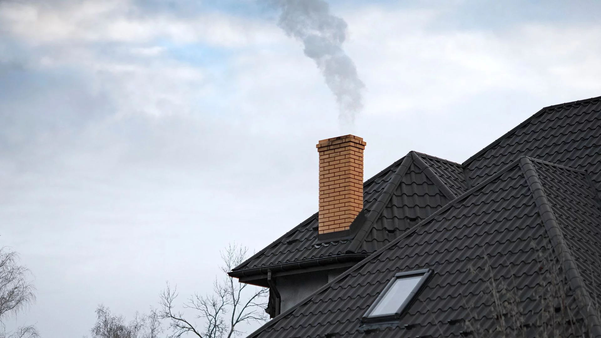Zmiany w programie Czyste Powietrze. Nawet 83 tys. zł na remont domu. Dym unoszący się z komina na dachu.