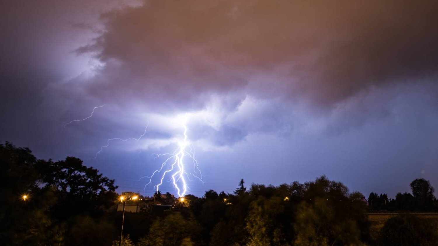 Piorun i ciemna burza nad miastem. Wyładowanie atmosferyczne uderza w ziemię.