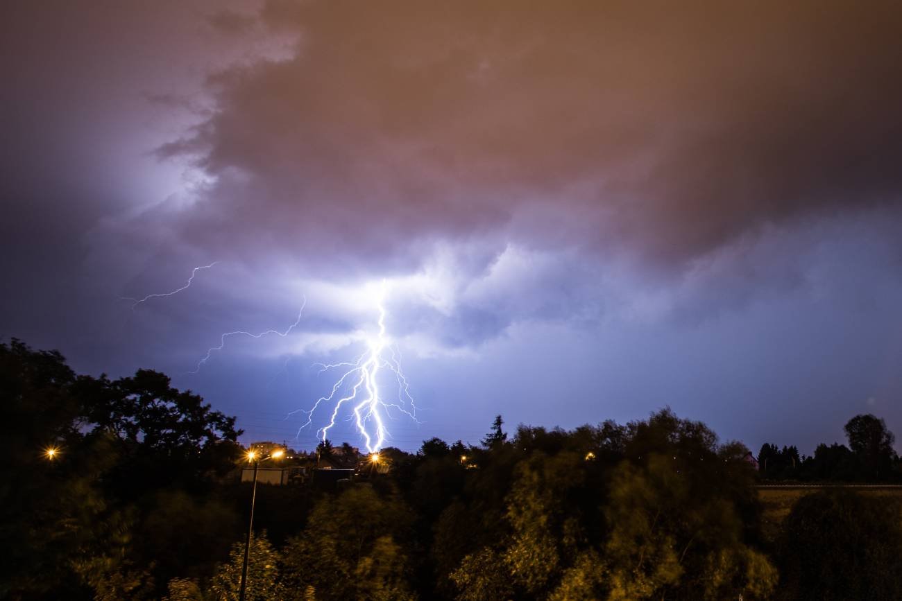 Piorun i ciemna burza nad miastem. Wyładowanie atmosferyczne uderza w ziemię.