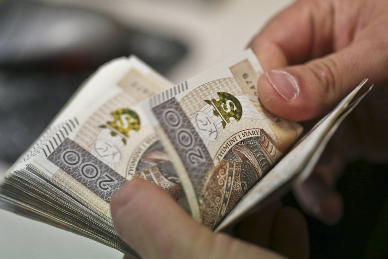 ręka licząca plik banknotów