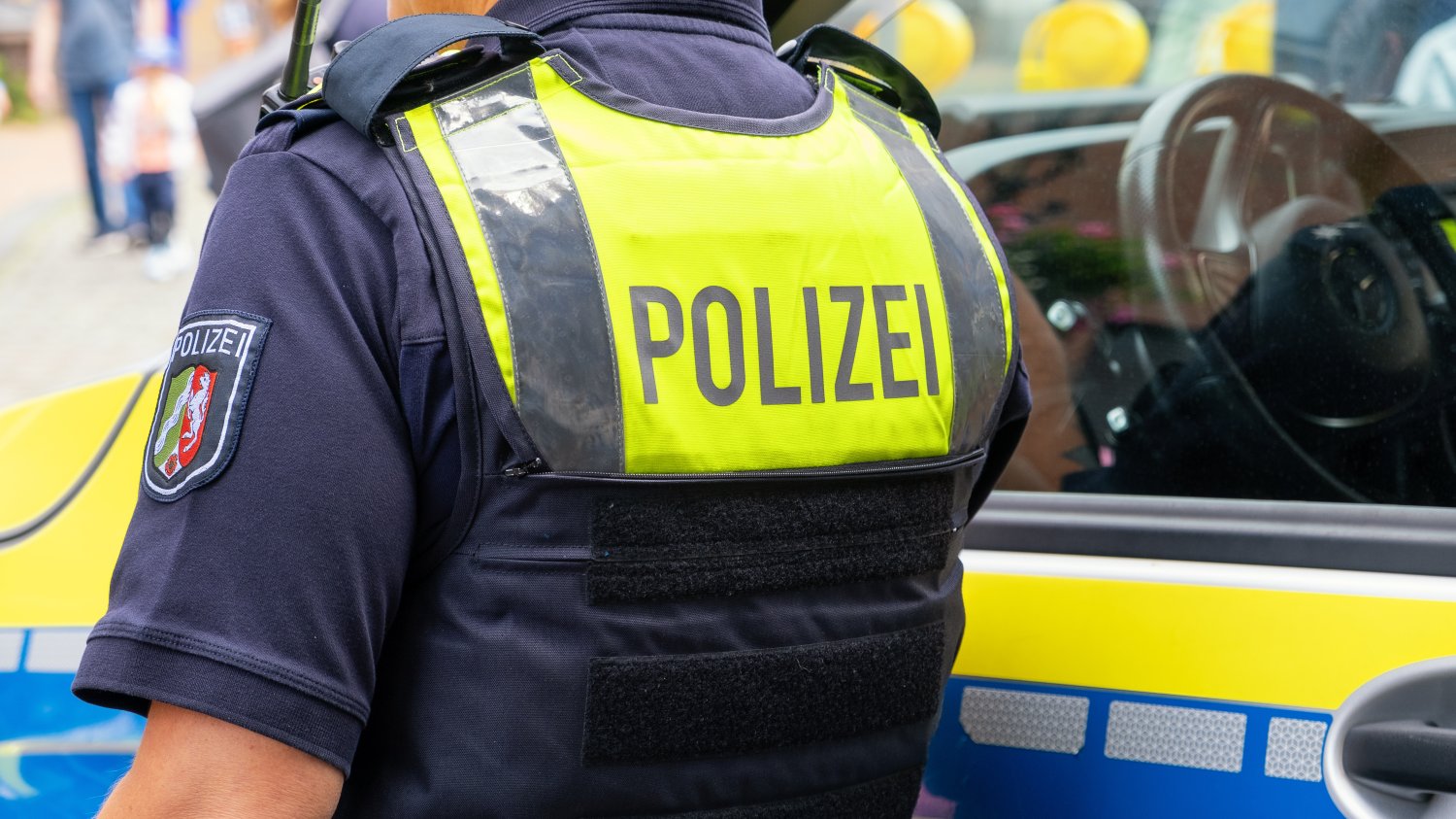 Niemiecka prasa krytykuje kontrole na granicy. Shengen skrzypi jak stara brama Mężczyzna, niemiecki policjant w kamizelce z napisem Polizei. Stoi tyłem obok niemieckiego pojazdu policyjnego.