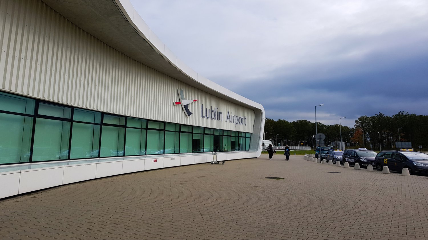 MON z ofertą za teren pod bazę śmigłowców w Lublinie. Lotnisko Lublin i nowe przeznaczenie. Budynek Lotnisko Lublin i taksówki. Ludzie w kurtkach w oddali.