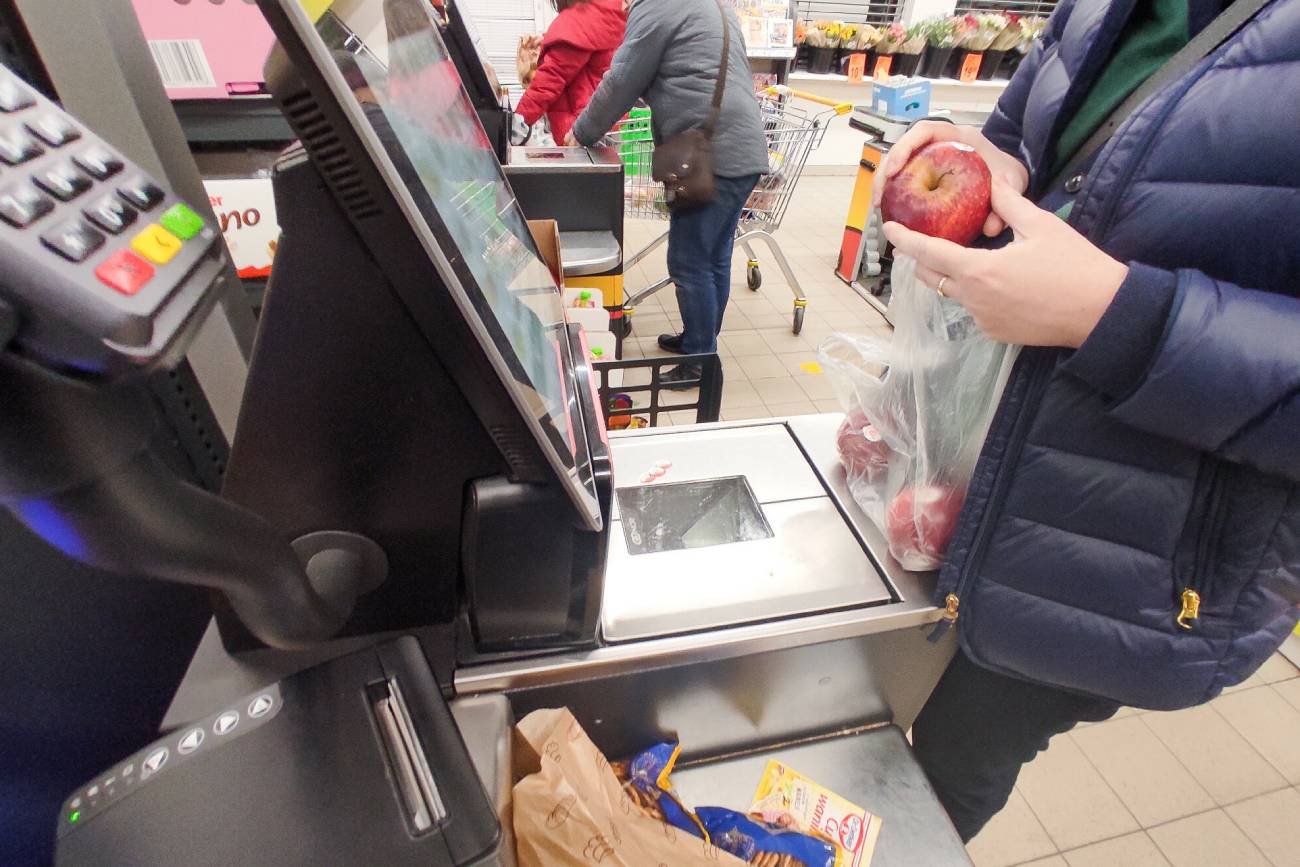 Osoba kupująca jabłko przy kasie samoobsługowej
