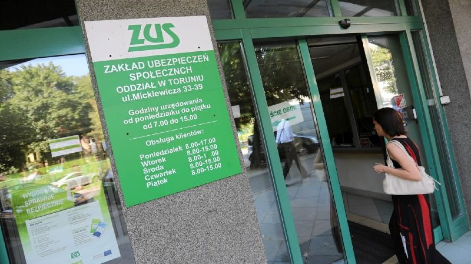 Kobieta wchodząca do budynku Zakładu Ubezpieczeń Społecznych.