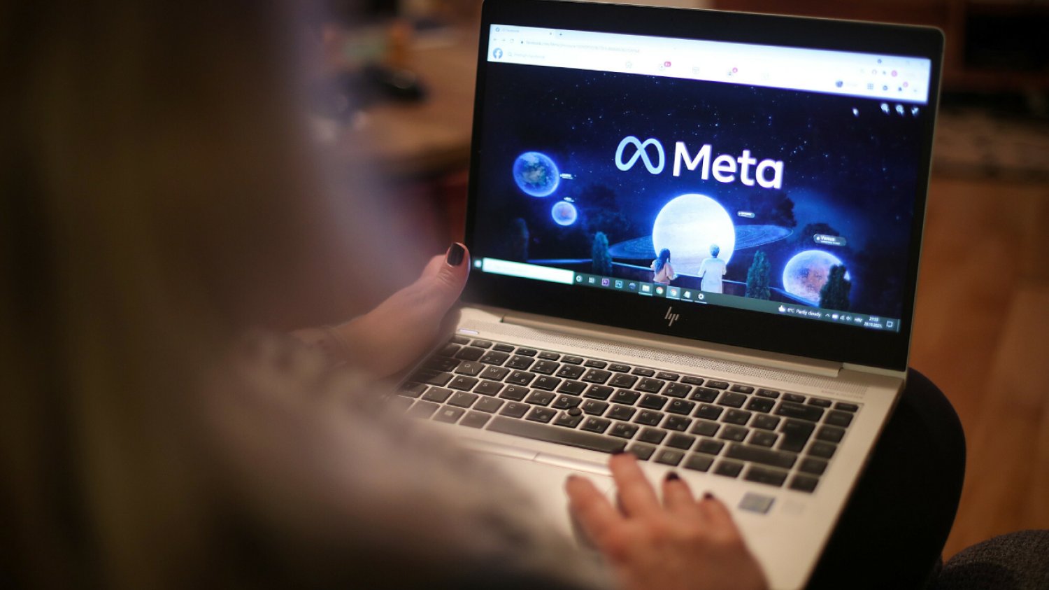 kobieta patrzy na laptop z otworzoną kartą Facebook Meta i kilka w ikony na monitorze przenośnego komputera