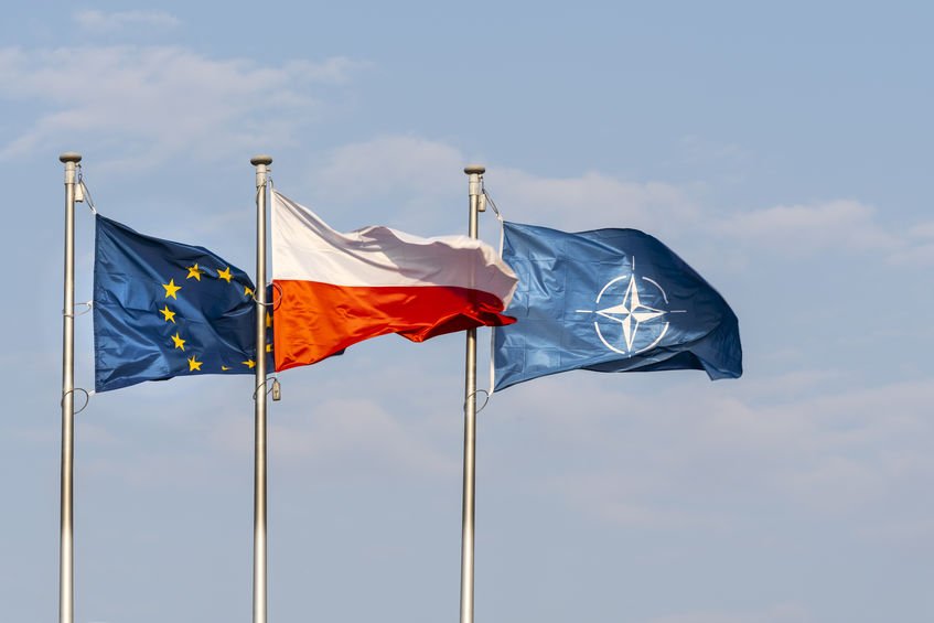 Flagi Unii Europejskiej, Polski i NATO powiewające na wietrze.