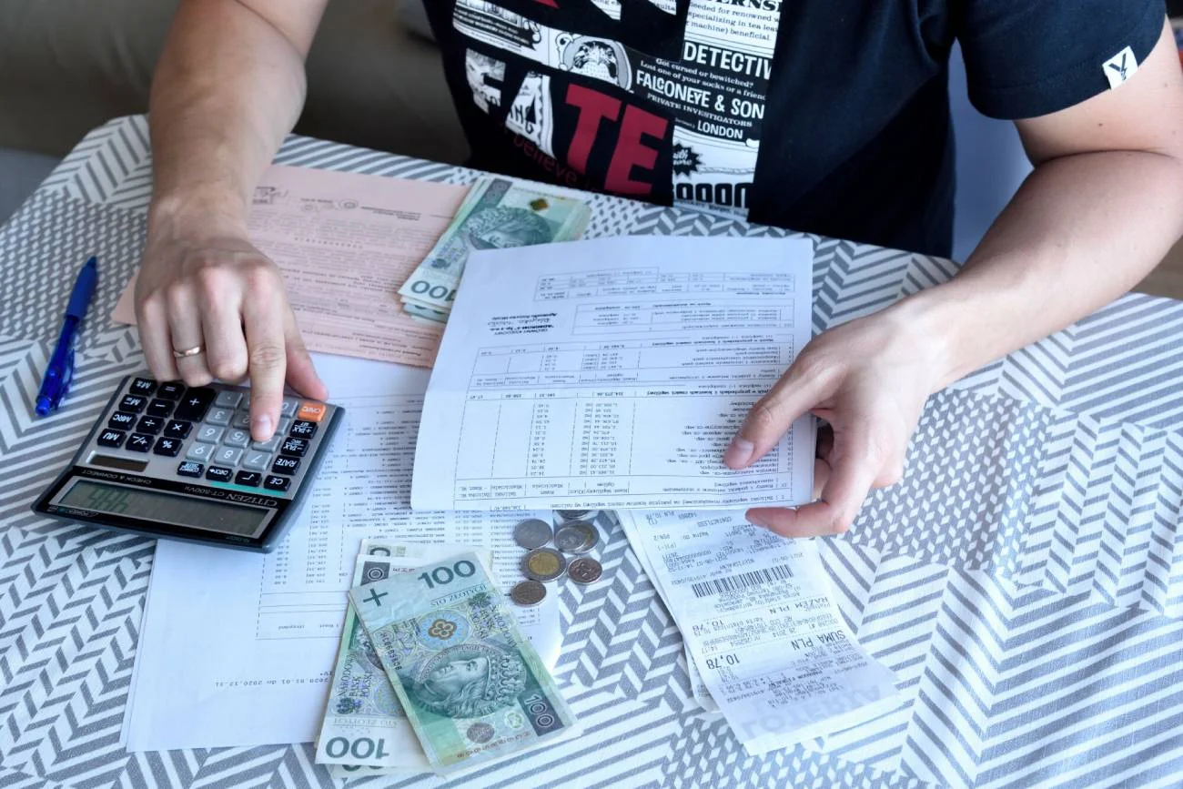 mężczyzna liczy na kalkulatorze łączny koszt rachunków