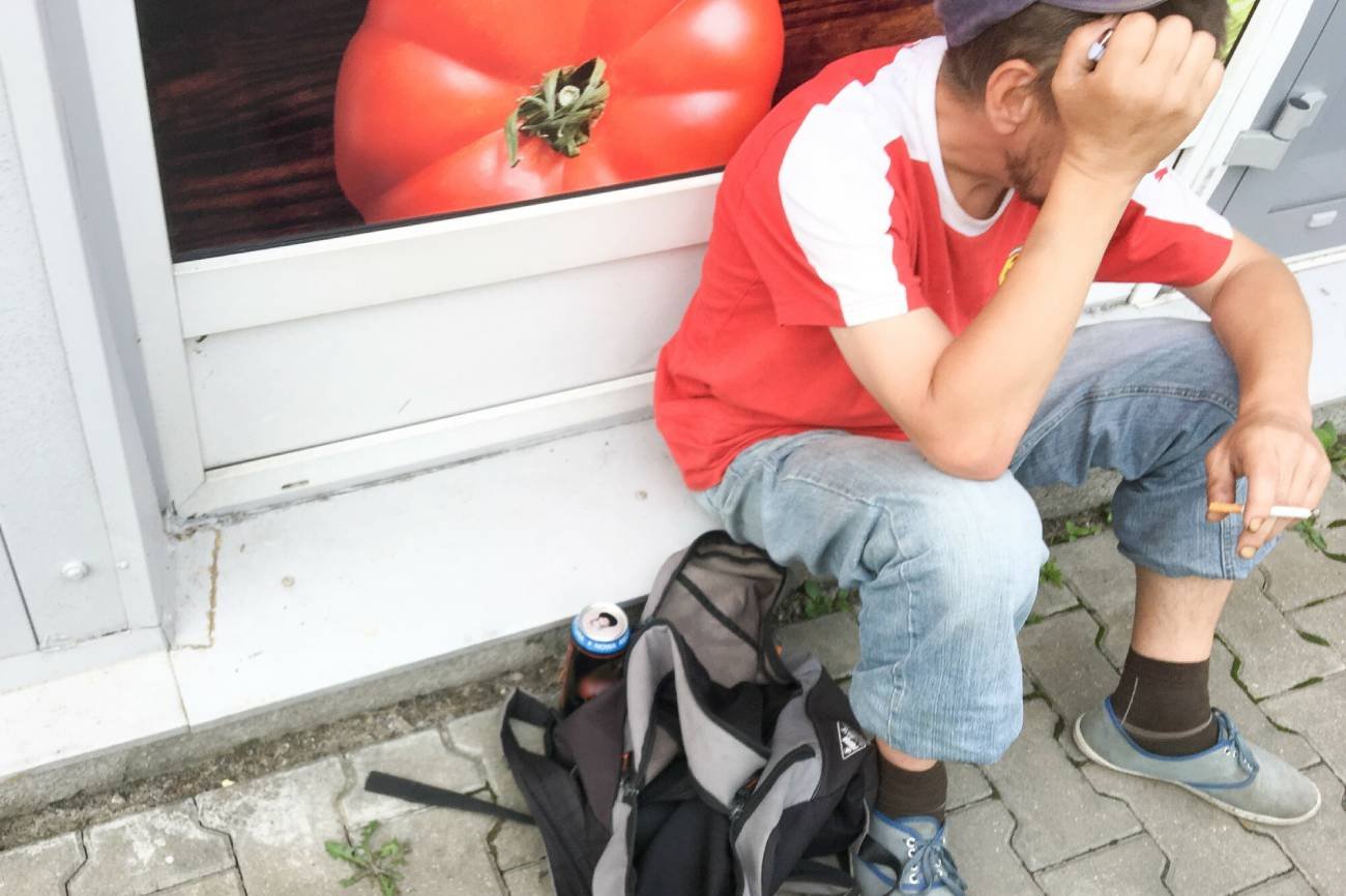 Mężczyzna z piwem pod sklepem.