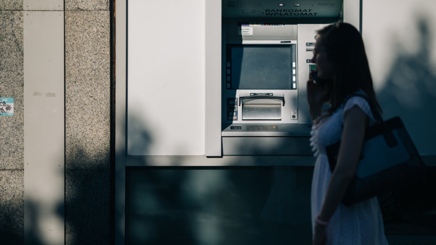 Kobieta przechodząca obok bankomatu