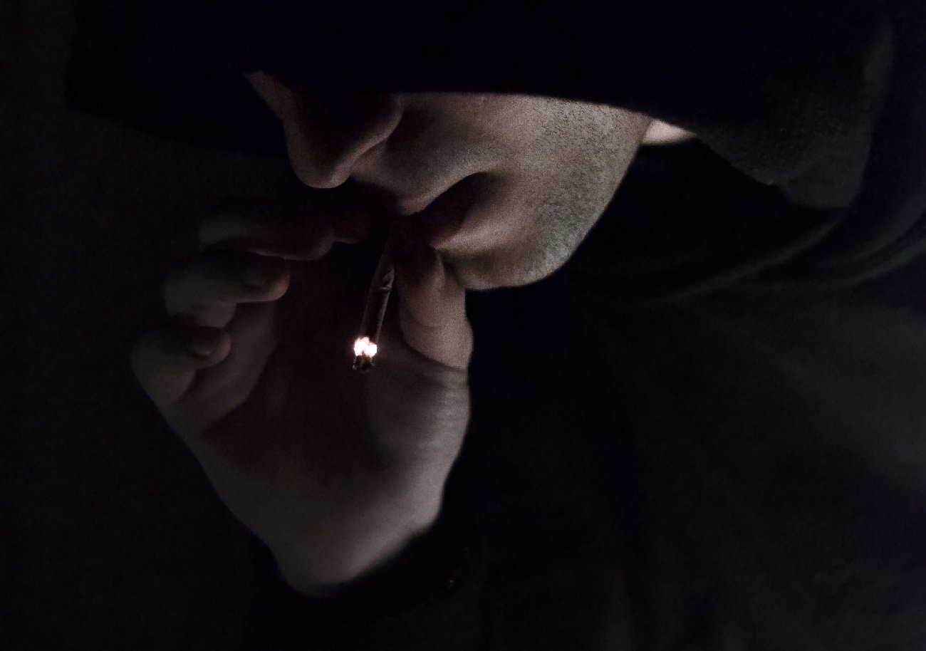 Zakapturzony mężczyzna pali.