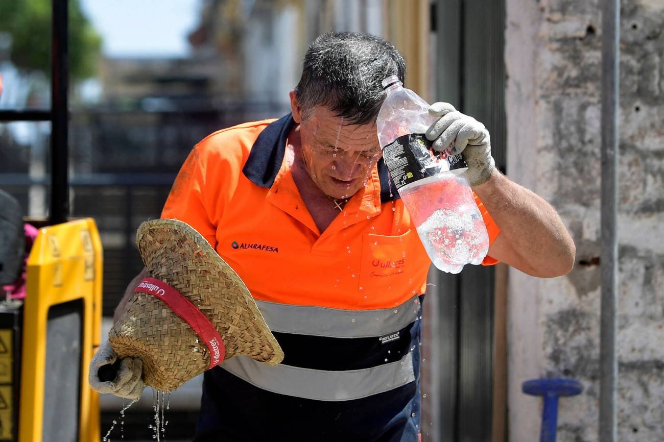 Robotnik polewający się wodą.