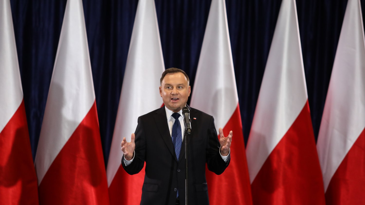 portret Prezydenta RP Andrzeja Dudy na tle polskich biało-czerwonych flag, na spotkaniu z wyborcami