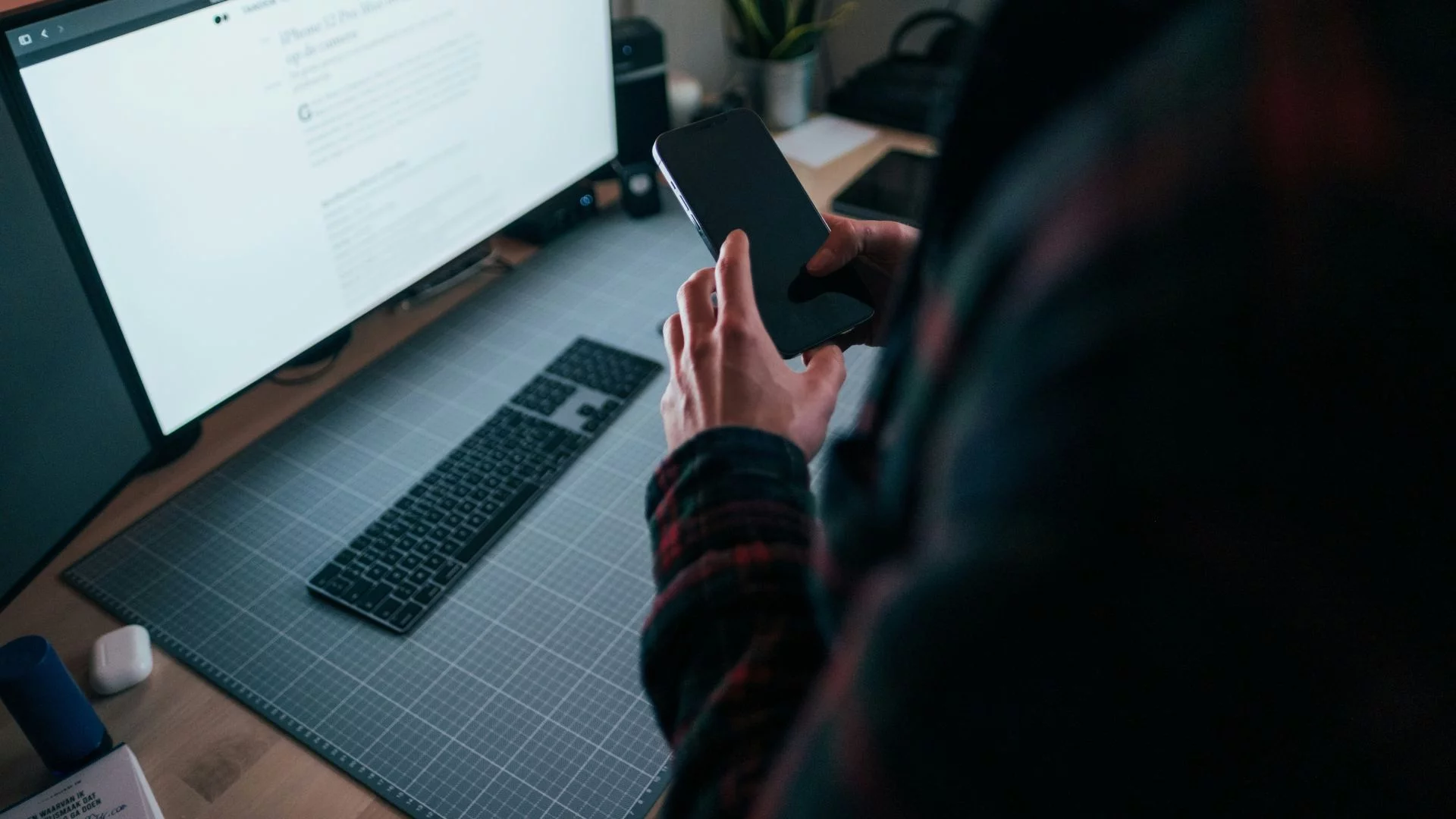 Osoba trzymająca smartfon przed monitorem komputera. Unijny pomysł chat controll nie przeszedł.