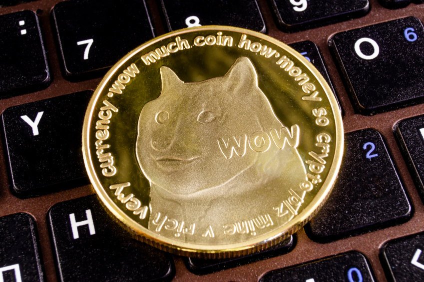 Dogecoin w formie fizycznej monety leżący na klawiaturze laptopa