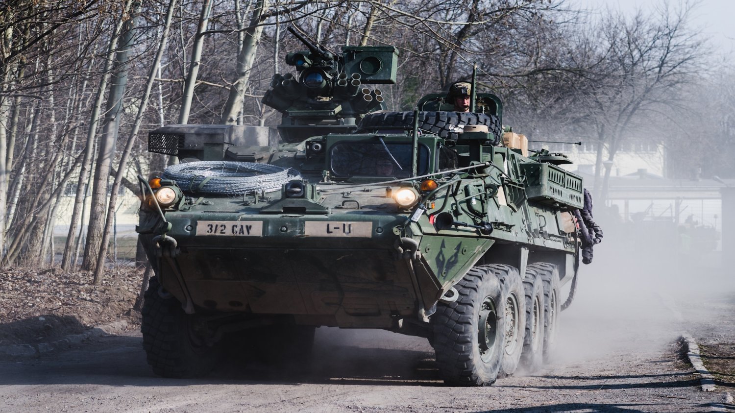 Jadący po drodze leśnej pojazd opancerzony Stryker z żołnierzami w środku. Hub armii USA na Śląsku. Pancerne bestie w polskich rękach
