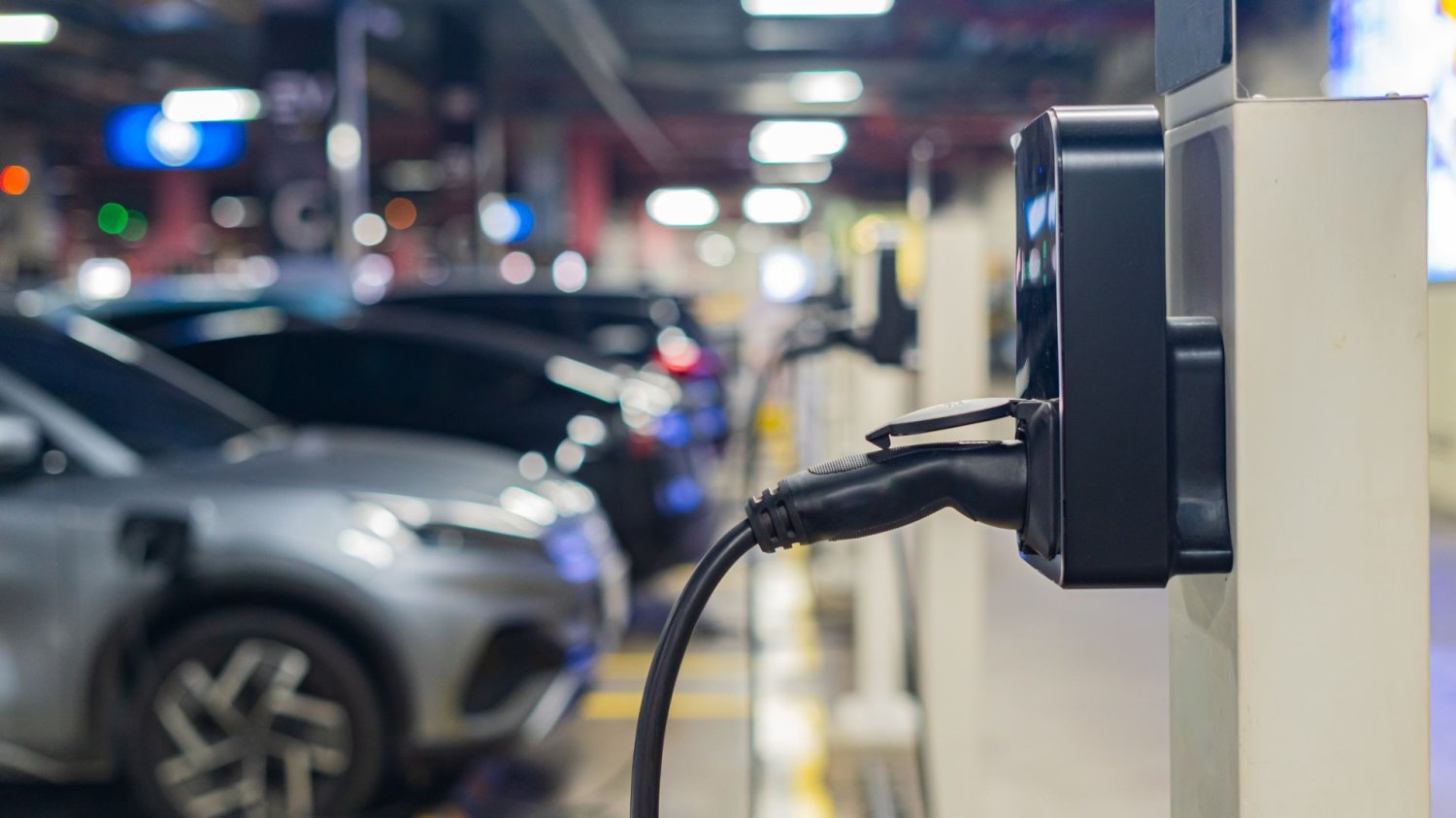 Samochody elektryczne na parkingu i stacja ładowania.