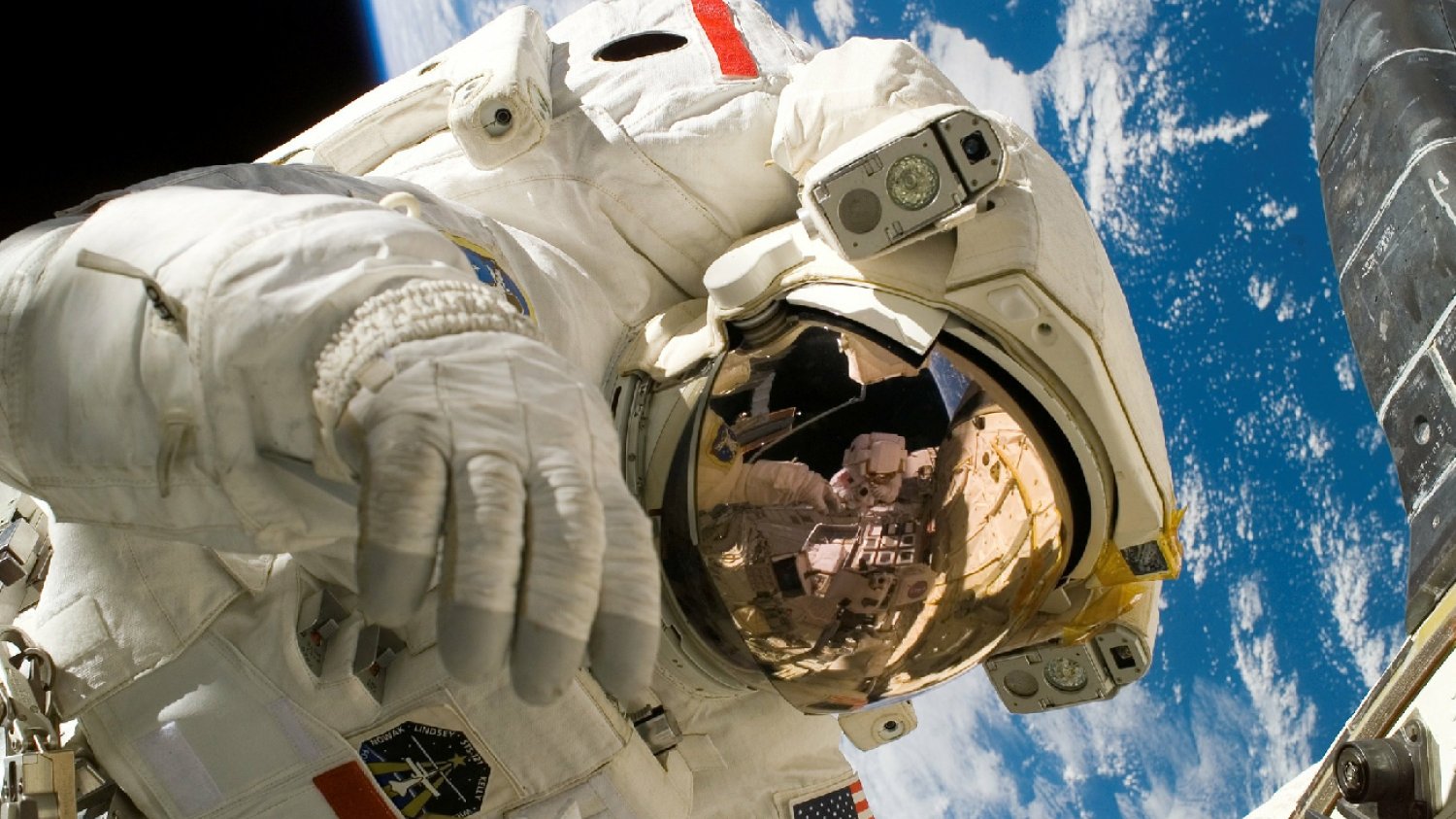 astronauta w białym kombinezonie na tle planety Ziemia unosi się w stanie nieważkości w kosmosie