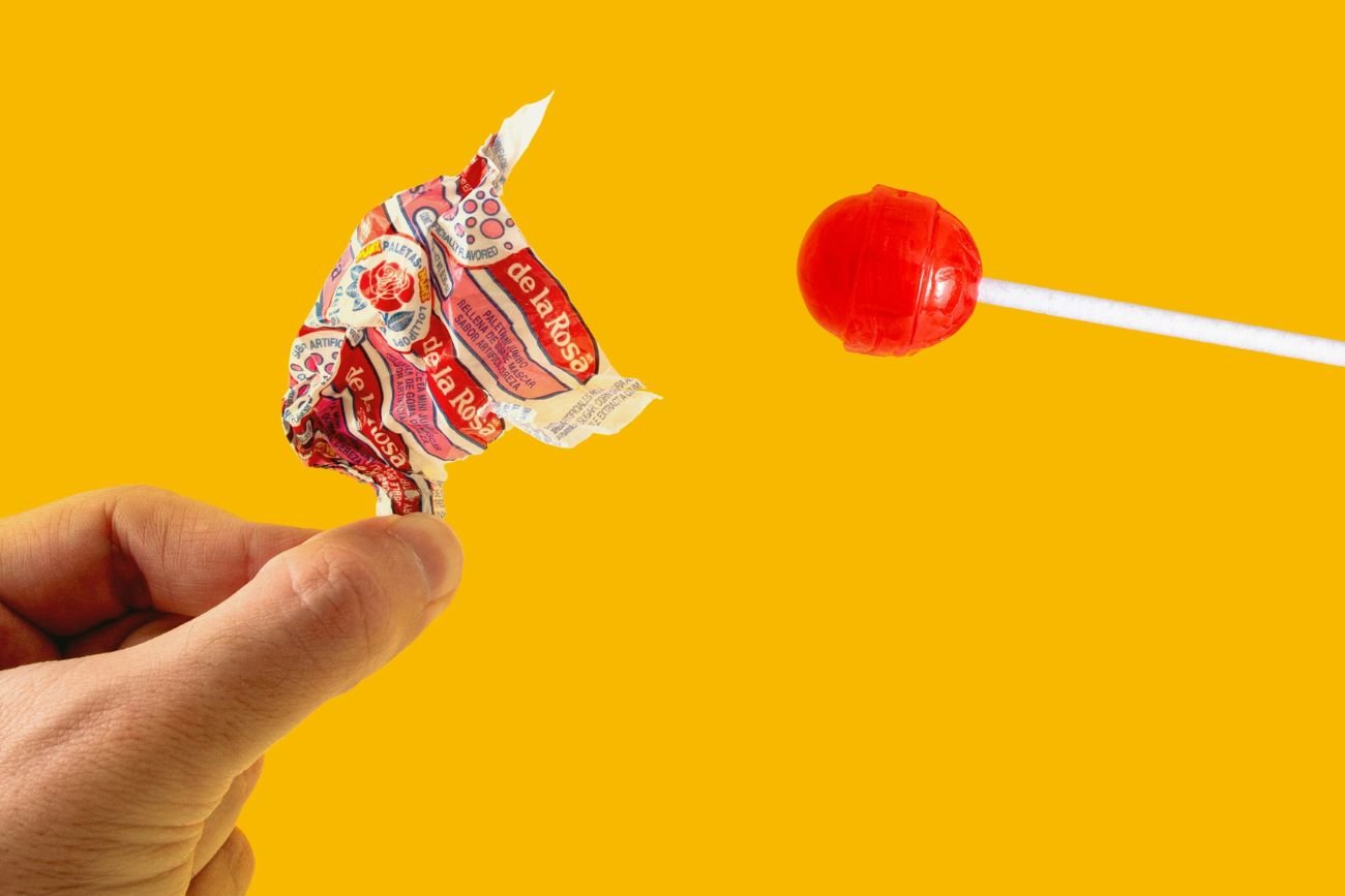 Czerwony lizak rozpakowywany na żółtym tle.