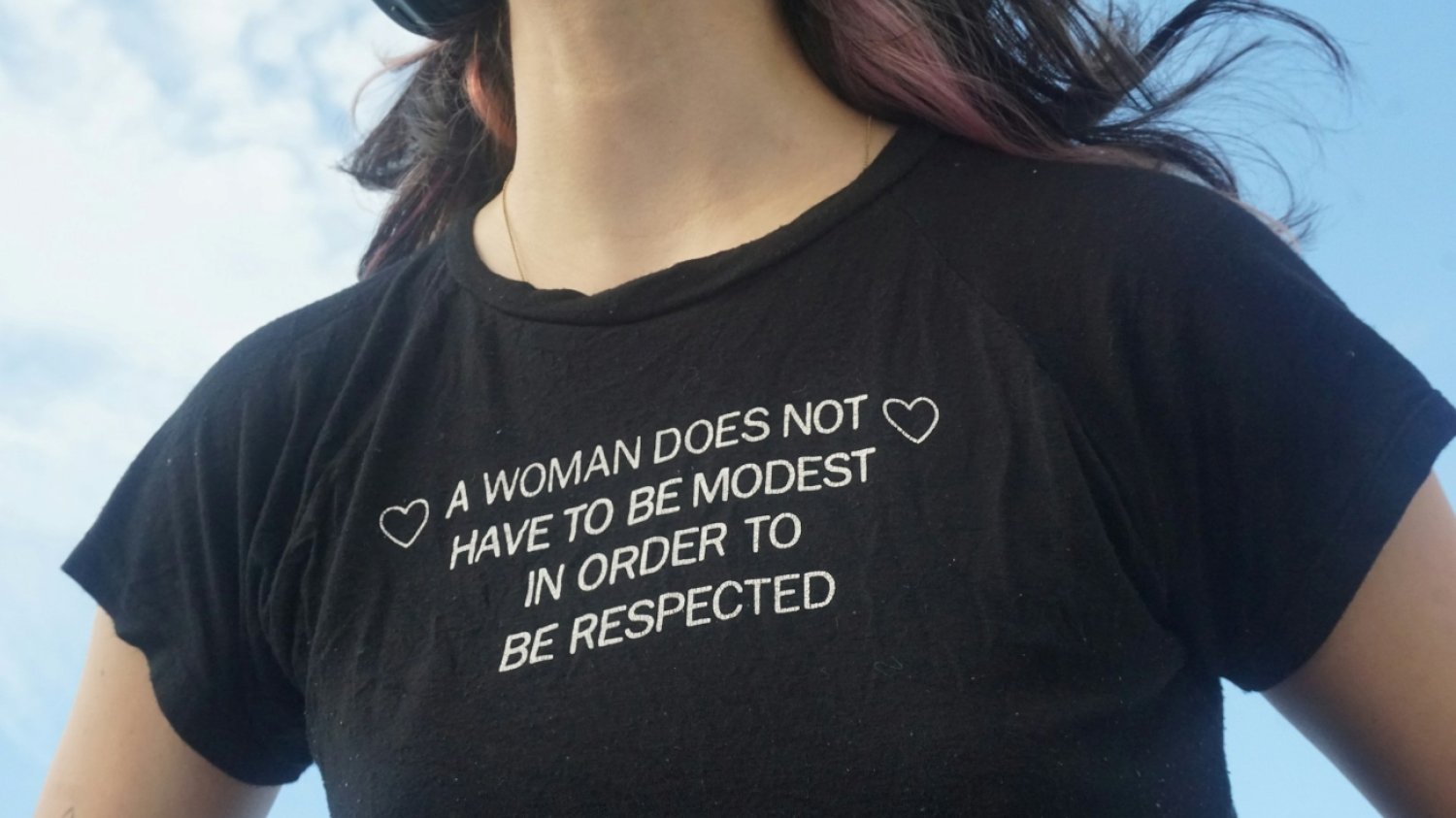 Kobieta w tshircie z napisem po angielsku, który można przetłumaczyć jako: Kobieta nie musi być skromna, by była szanowana.