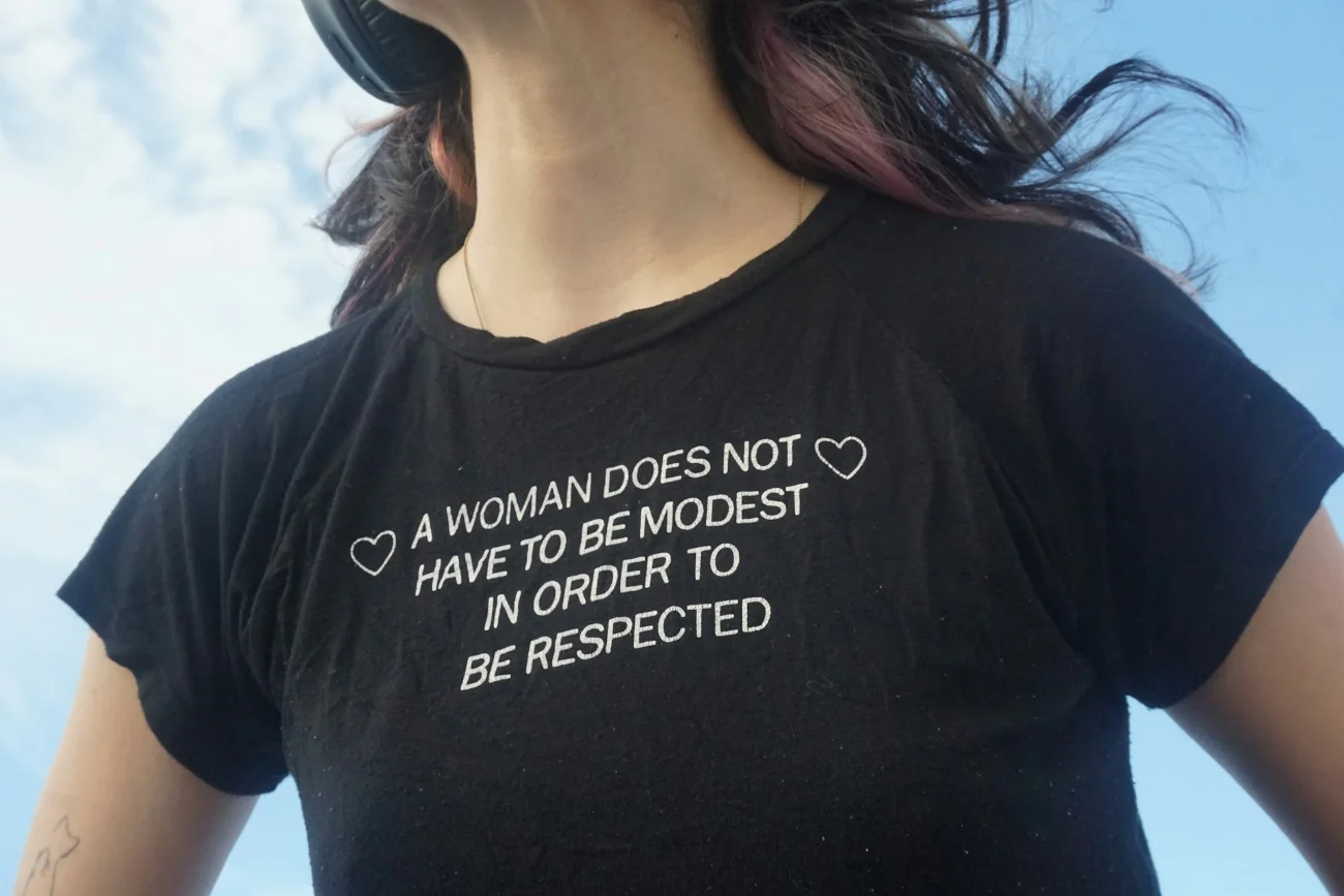 Kobieta pozywa Google. Wyrok może być przełomowy dla innych kobiet i bigtechów. Kobieta w tshircie z napisem po angielsku, który można przetłumaczyć jako: Kobieta nie musi być skromna, by była szanowana.