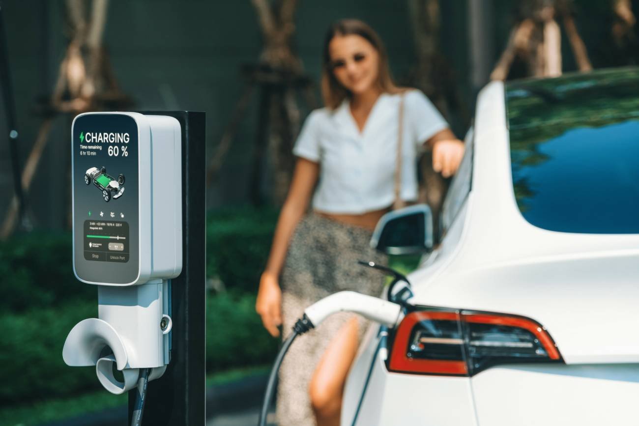 Kobieta przy stacji ładowania samochodu elektrycznego.