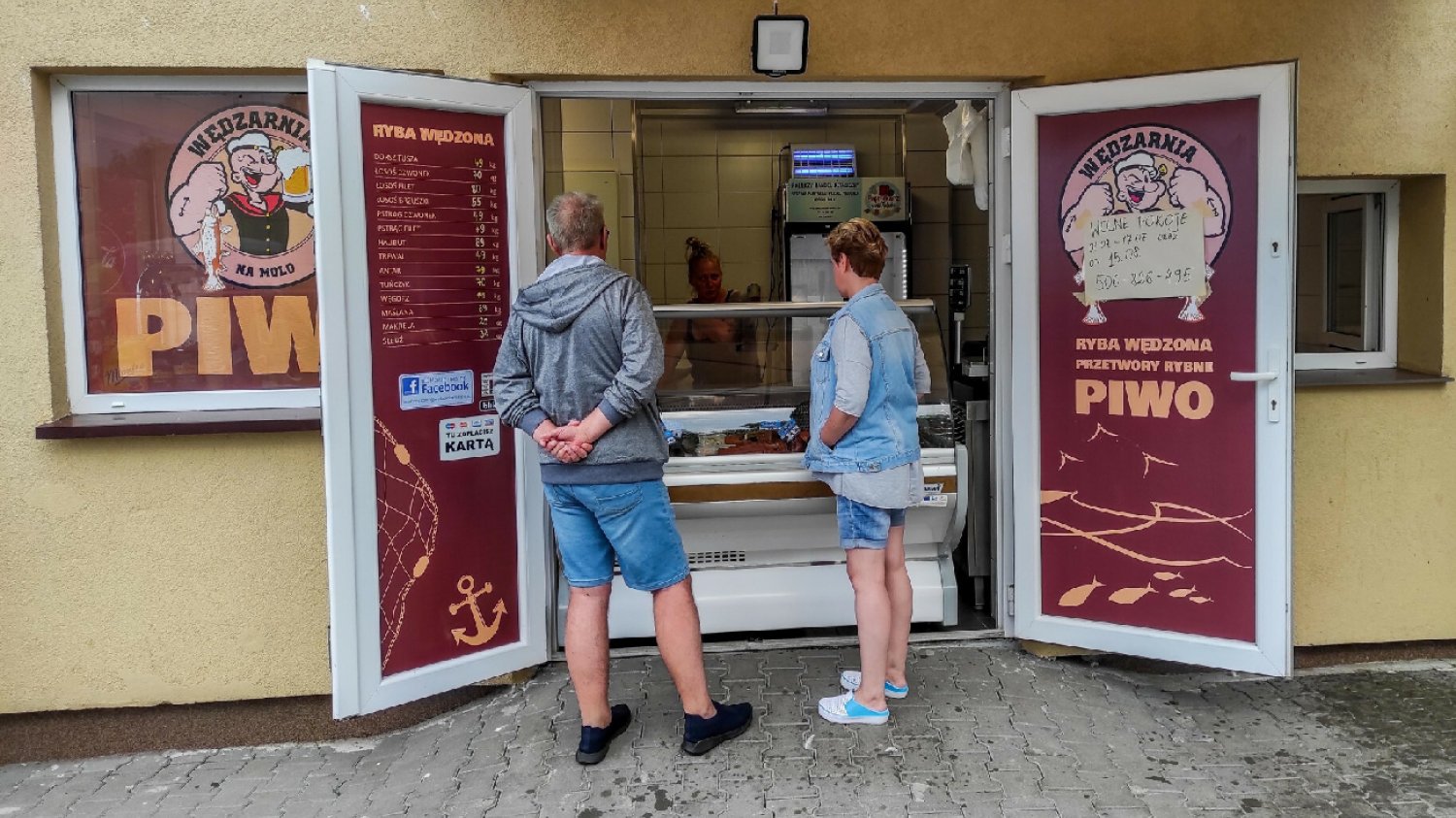 para kobieta i mężczyzna kupuje alkohol w sklepie spożywczym w polskiej miejscowości turystycznej nad morzem bałtyckim