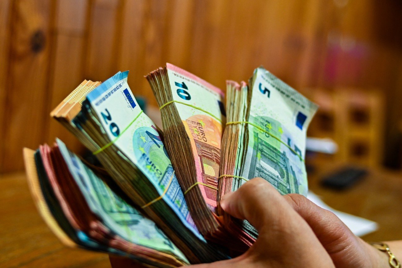 Trzymane w rękach pliki banknotów euro.