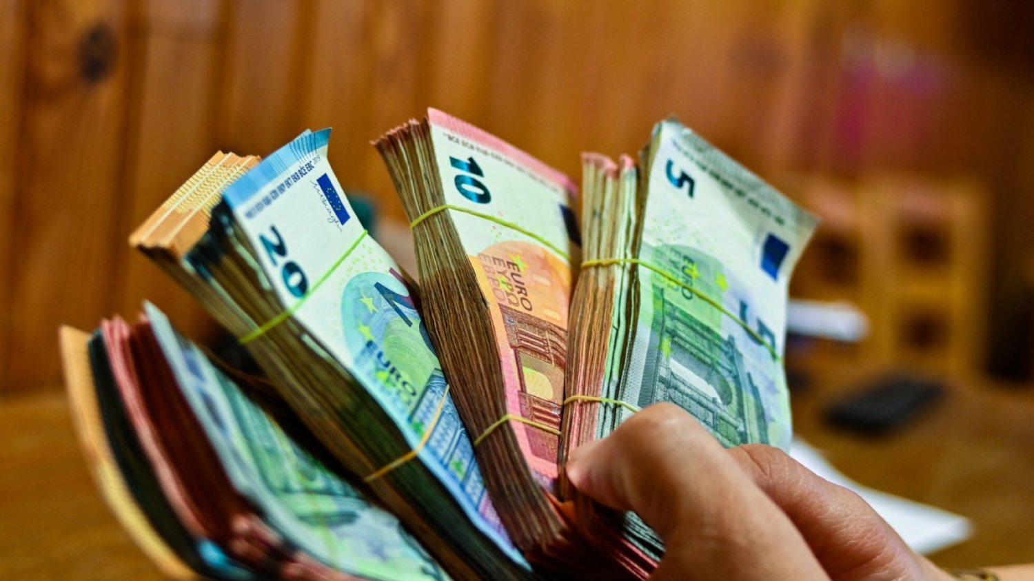 Trzymane w rękach pliki banknotów euro.
