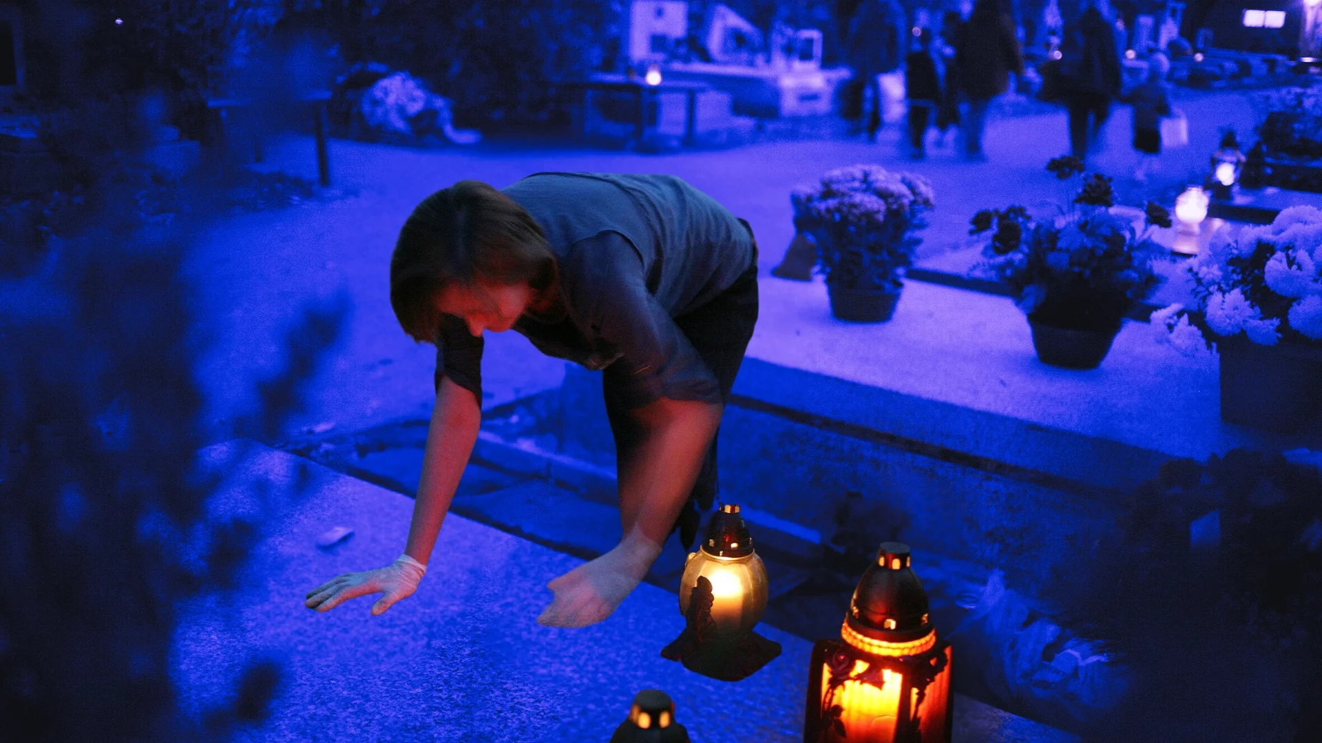 Kobieta wyciera płytę nagrobną. Istnieją specjalne firmy, w których można wykupić usługi porządkowe na cmentarzu.