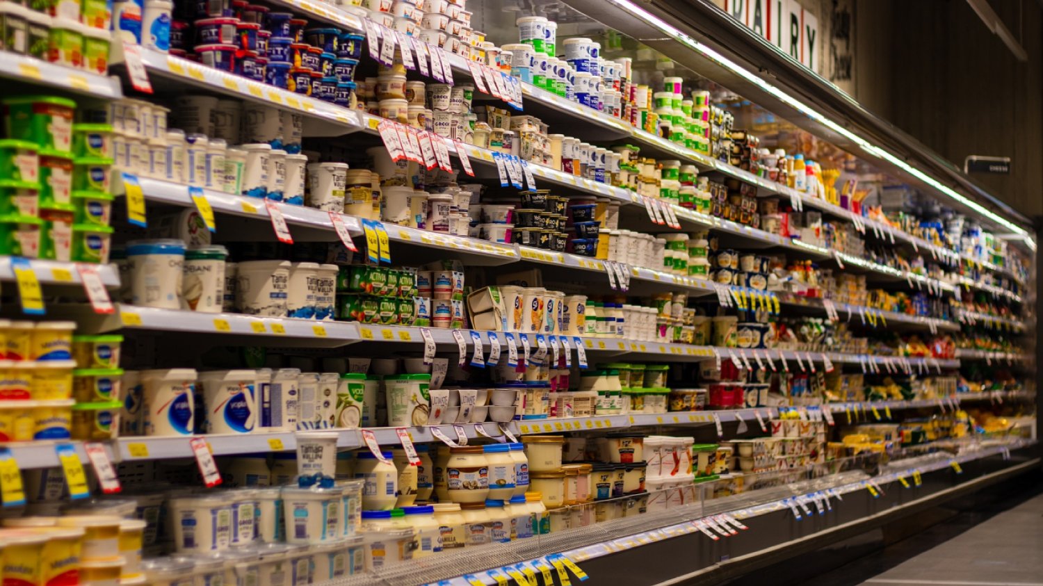 Półki w supermarkecie zapełnione produktami spożywczymi.
