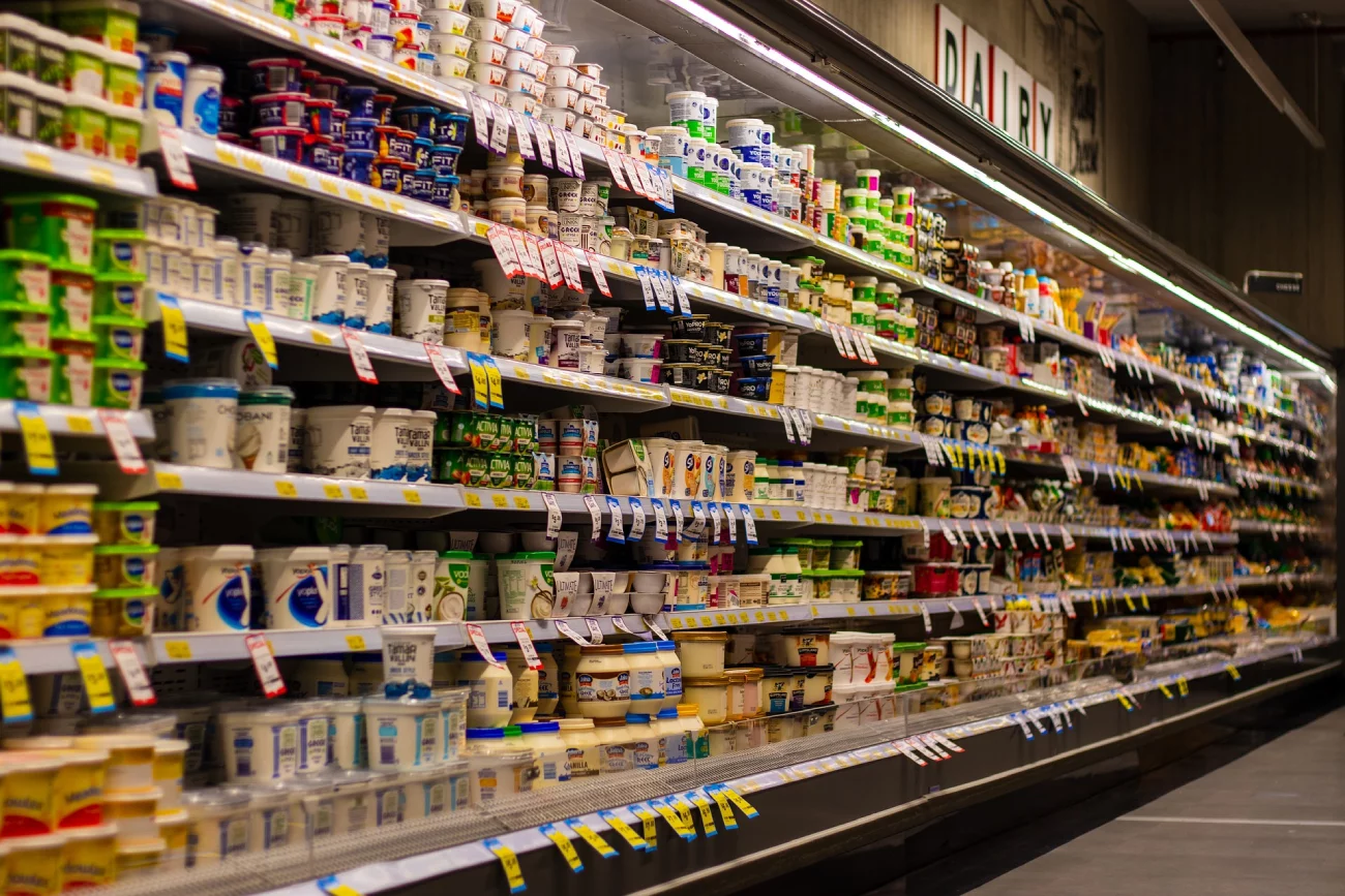 Półki w supermarkecie zapełnione produktami spożywczymi.