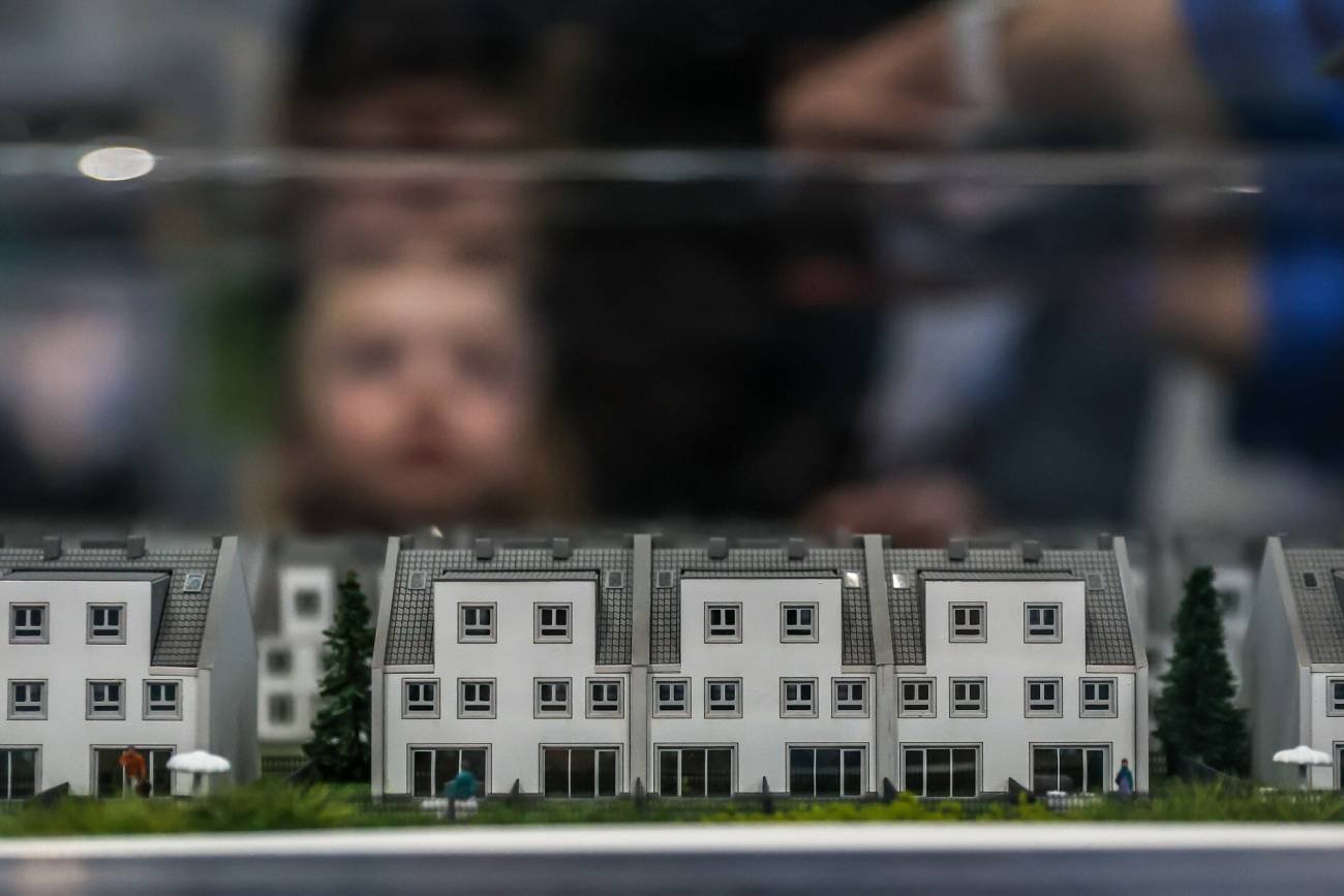 Makiety mieszkań na targach. Ktoś ogląda je przez szybę.