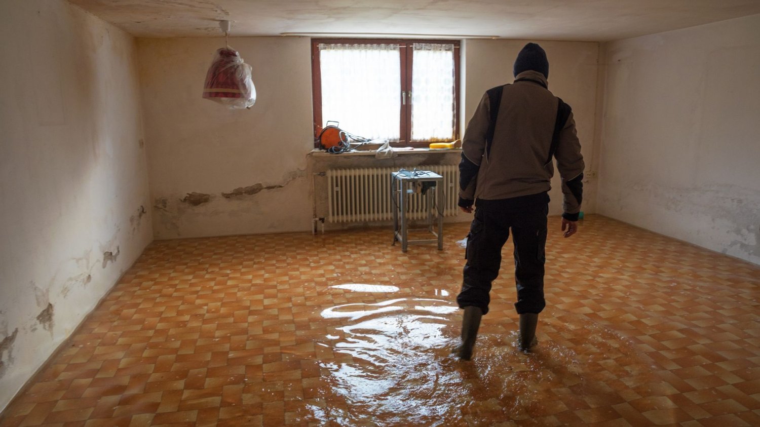 Unijne miliony dla Krakowa. Mieszkańcy Nowej Huty poczują ulgę. Mężczyzna chodzi po zalanym pomieszczeniu.