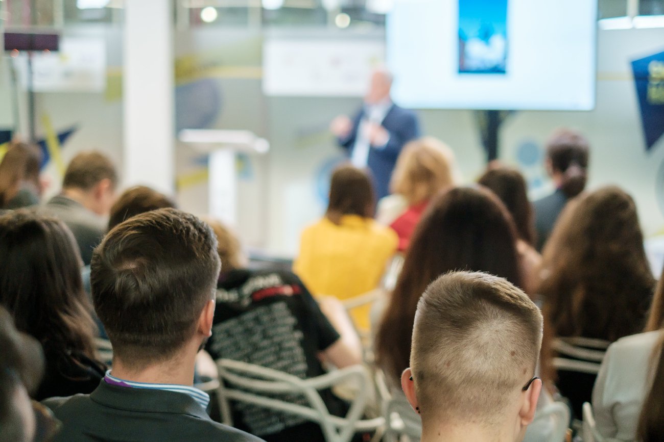 ludzie siedzący na wystąpieniu publicznym w auli