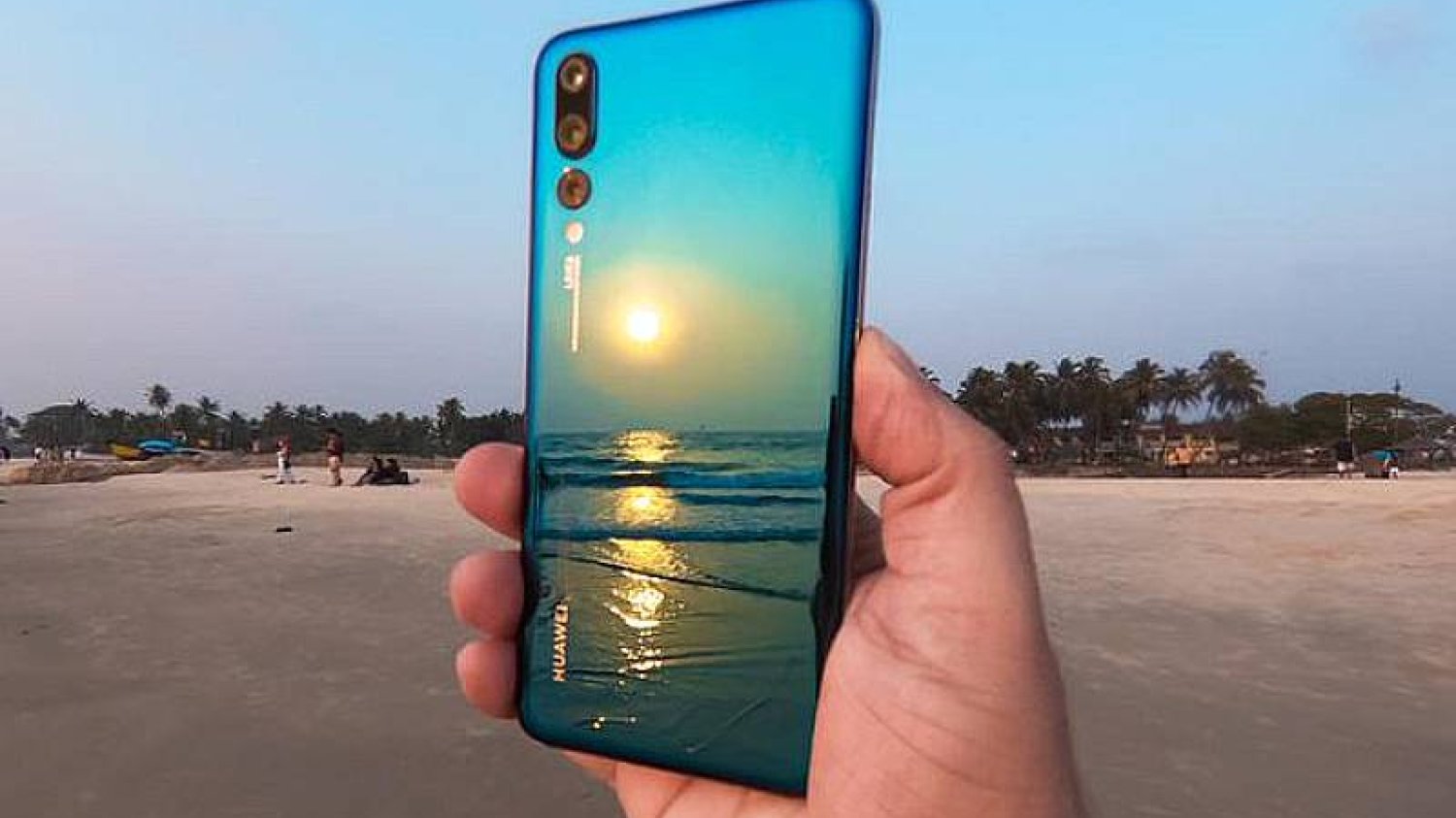 Huawei P20 Pro w ręce. Plaża i zachód słońca na tropikalnym wybrzeżu.