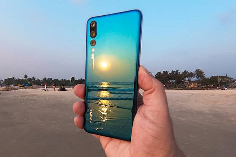 Huawei P20 Pro w ręce. Plaża i zachód słońca na tropikalnym wybrzeżu.