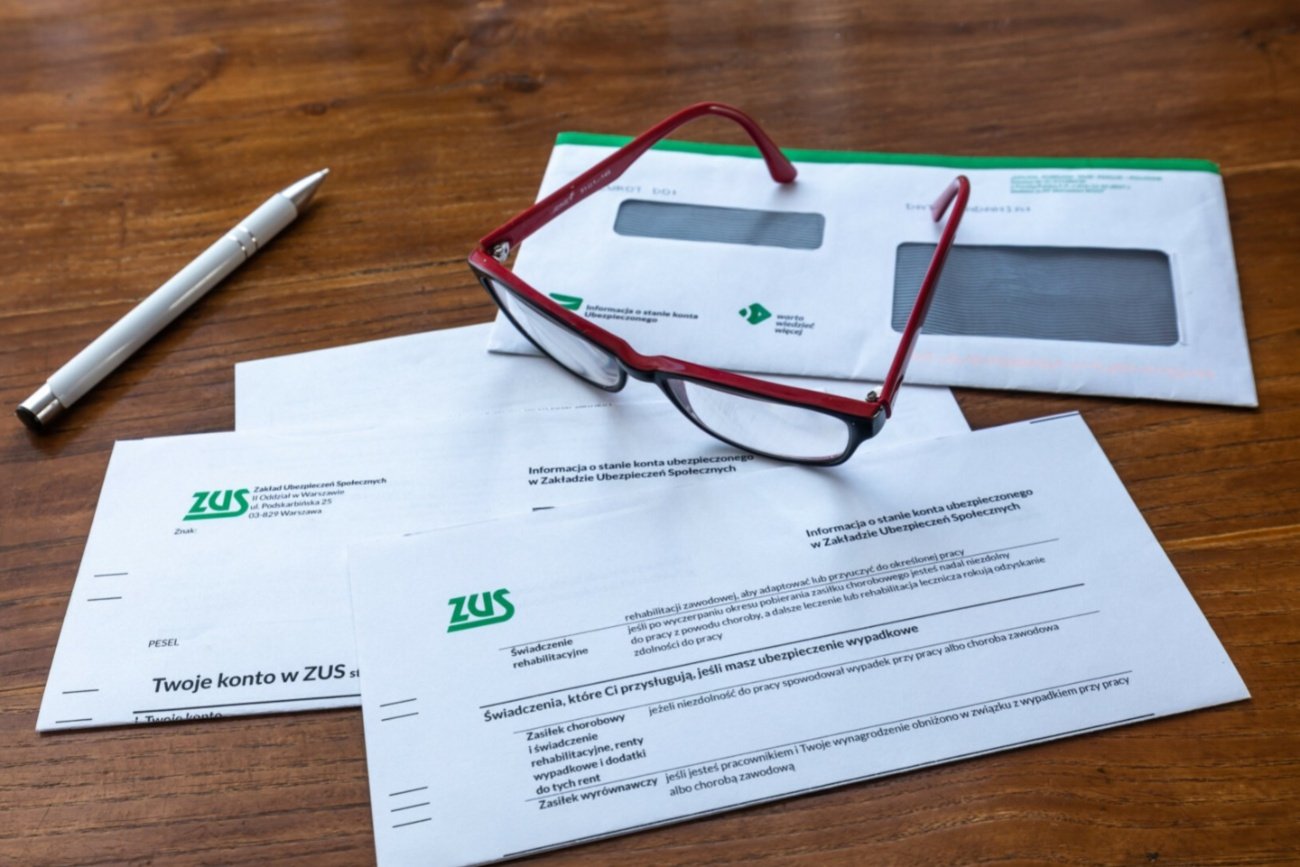 Dokumenty z ZUS, długopis, okulary.