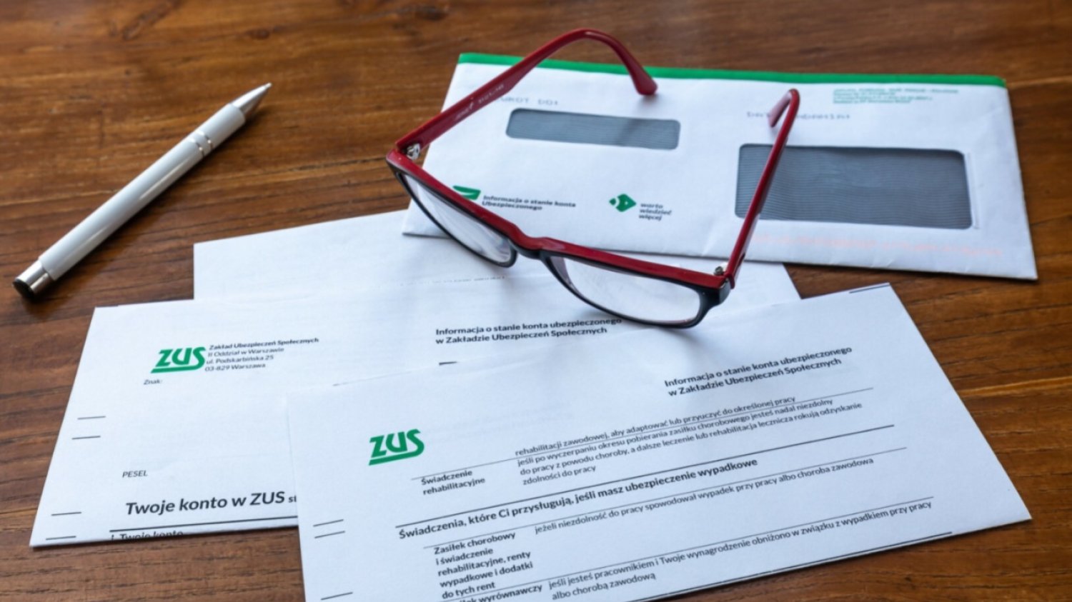 Dokumenty z ZUS, długopis, okulary.