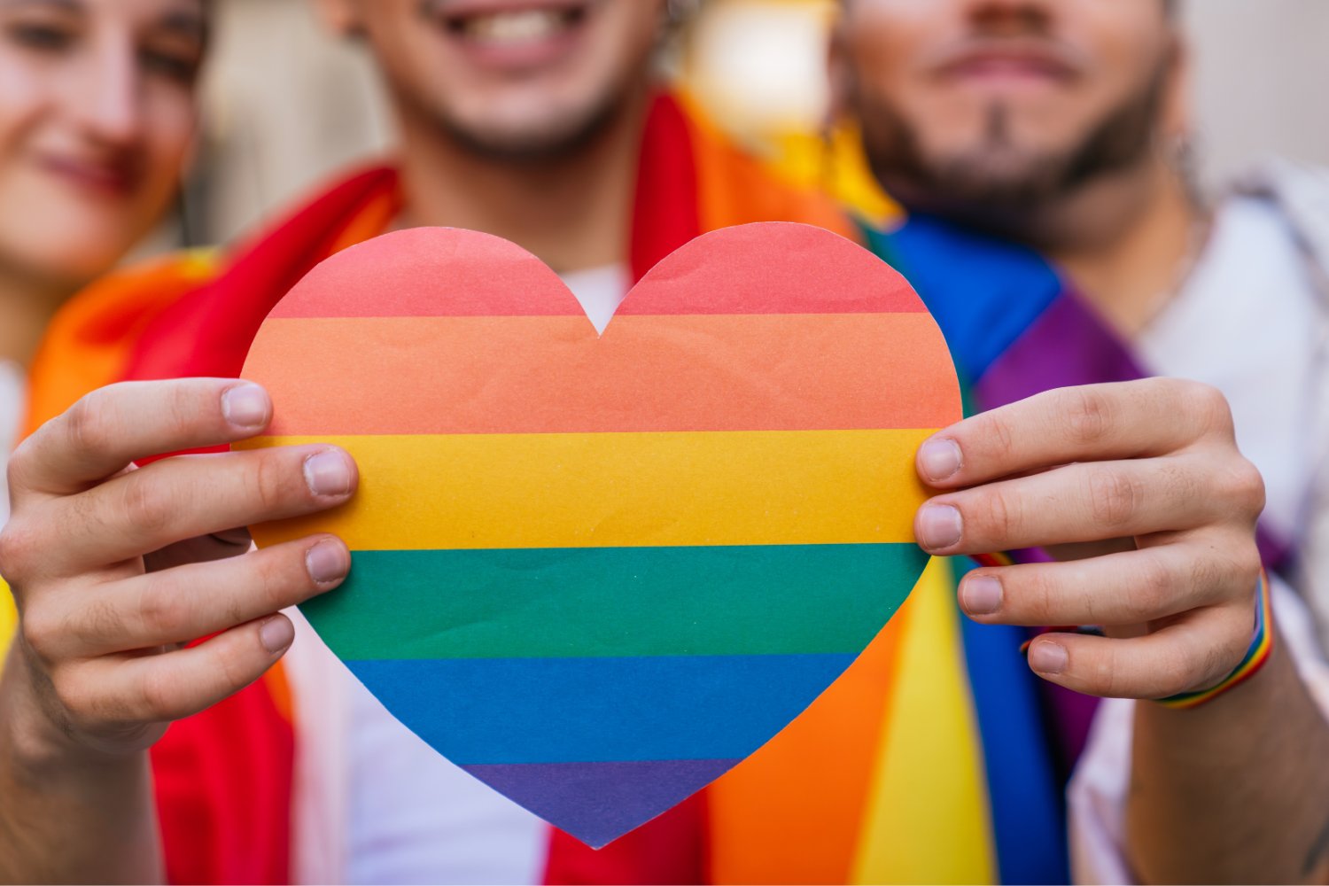 Państwo uznało małżeństwo, ale fiskus odmówił ulgi. Mamy w Polsce nowy paradoks Serce w barwach flagi LGBT. W tle osoby trzymające te flage.