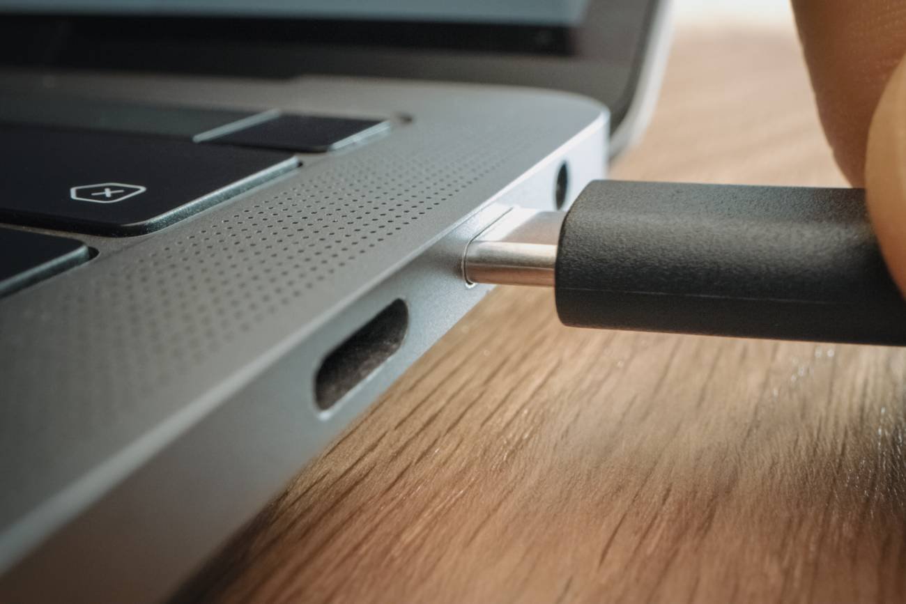 Ręka wkłada wtyczkę USB C do laptopa.