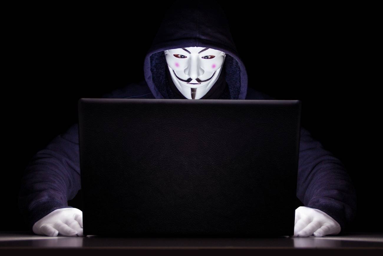 Haker w masce przed komputerem.