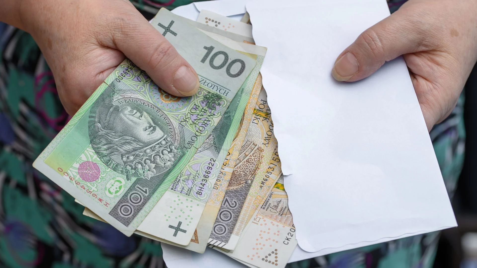 Świadczenie wspierające z ZUS bez kryterium dochodowego. Nawet 4353 zł trafia do Polaków. Kobieta trzyma w rękach kopertę z pieniędzmi.