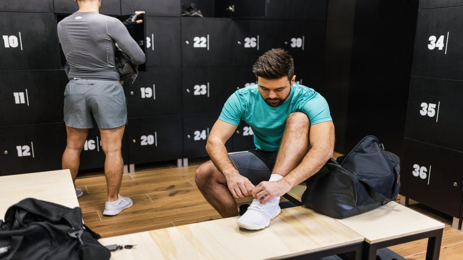 Ministerstwo Sportu rusza z programem „Szatnia na medal”. Mniejsze miejscowości zyskają nowe obiekty. Dwóch mężczyzn w szatni sportowej. Przebierają się.