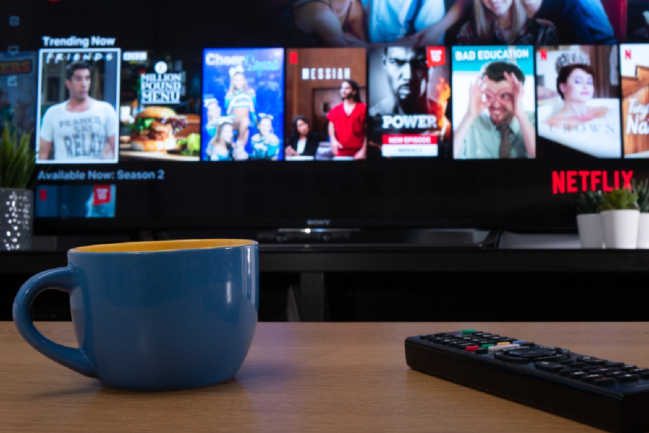 menu trendów Netflix wyświetlane na ekranie telewizora w domu z kubkiem i pilotem